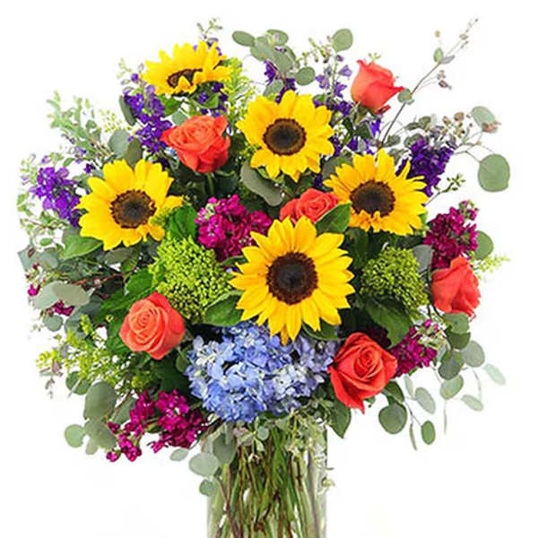 Bouquet of sunflowers, coral roses, and purple flowers in a glass vase