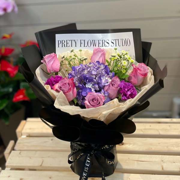 Bouquet of pink roses and purple hydrangea in black wrapping