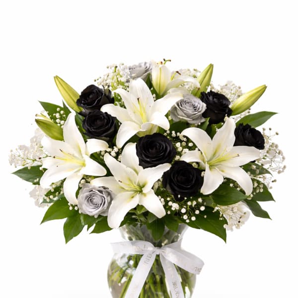 Bouquet of white lilies and black roses in a glass vase
