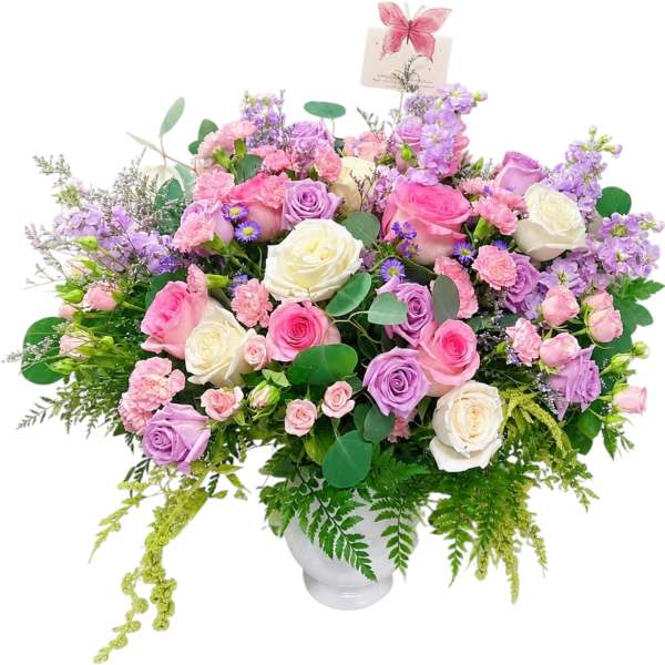Large pastel bouquet of roses, carnations, and purple flowers in a white vase