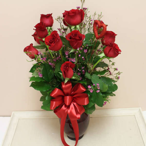 Red roses in a vase with a red ribbon bow