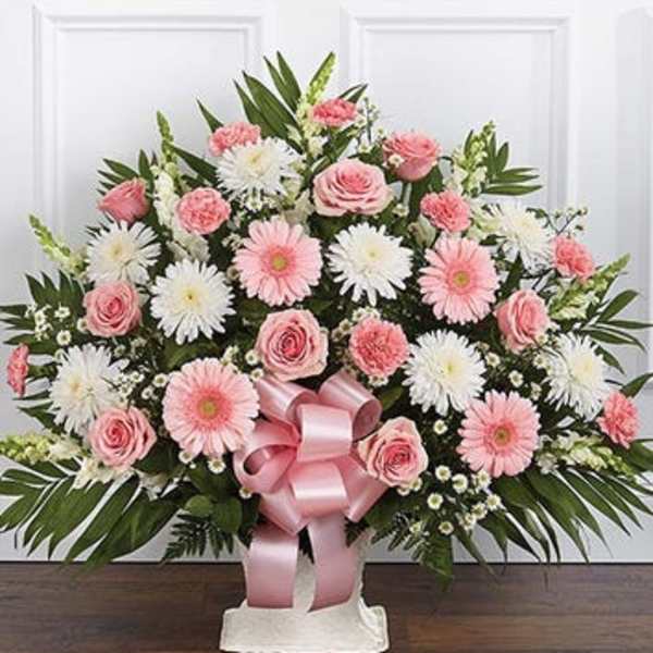 Pink and white floral standing spray with a pink ribbon on a white easel
