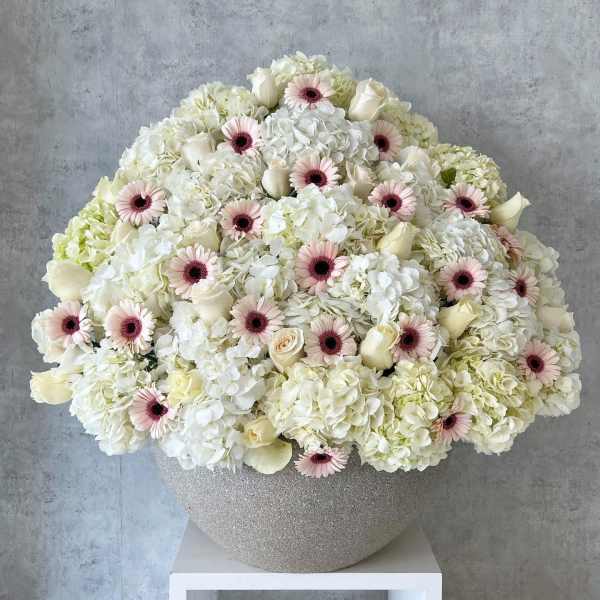 Large white floral arrangement with pale pink daisies in a glittery vase