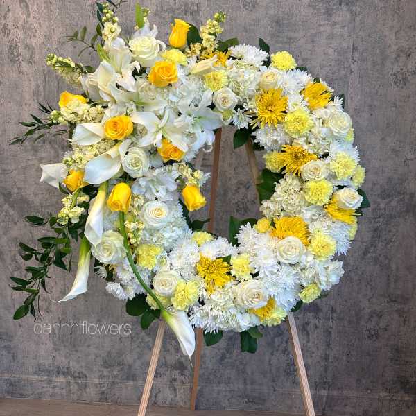 Large floral wreath on an easel with white and yellow flowers
