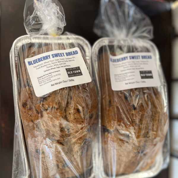 Two wrapped blueberry sweet bread loaves in foil pans