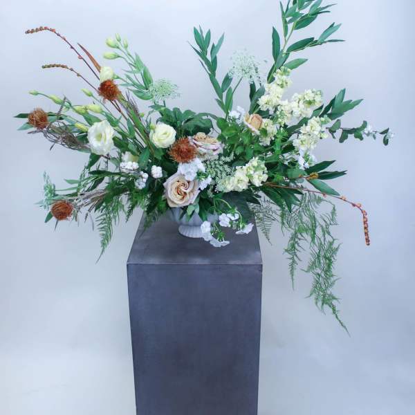 Large floral arrangement with white and peach blooms in a tall vase