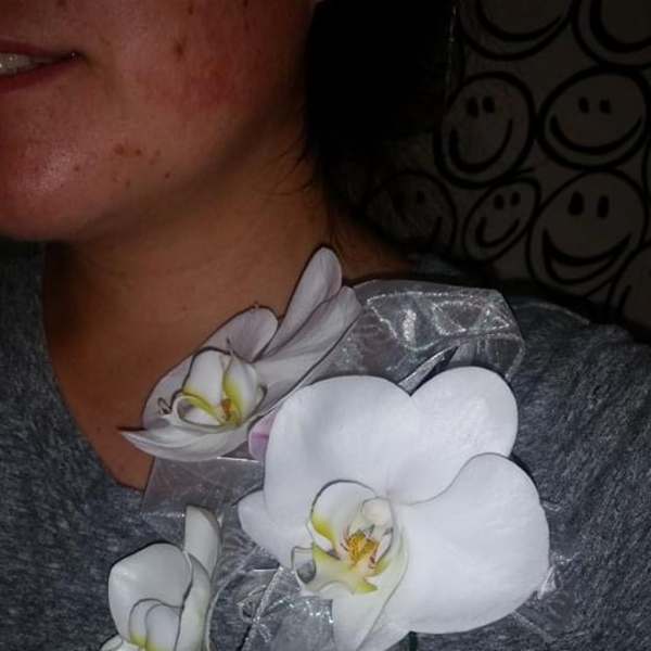 White orchid corsage with sheer ribbon on a person's shoulder