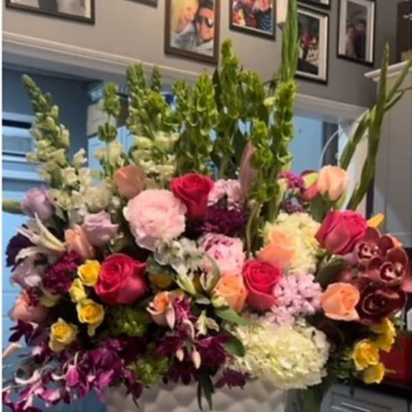 Large mixed bouquet in a white vase with pink, red, yellow, and purple flowers