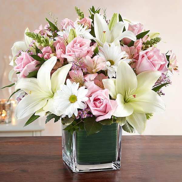 Pink roses and white lilies arranged in a clear glass vase