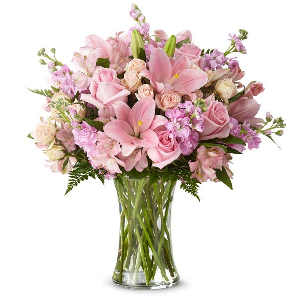 Pink roses and lilies arranged in a clear glass vase