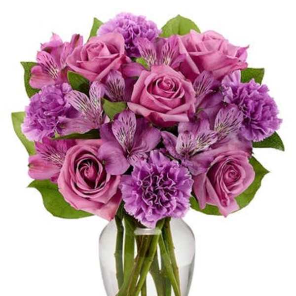 Pink and purple bouquet of roses and carnations in a glass vase