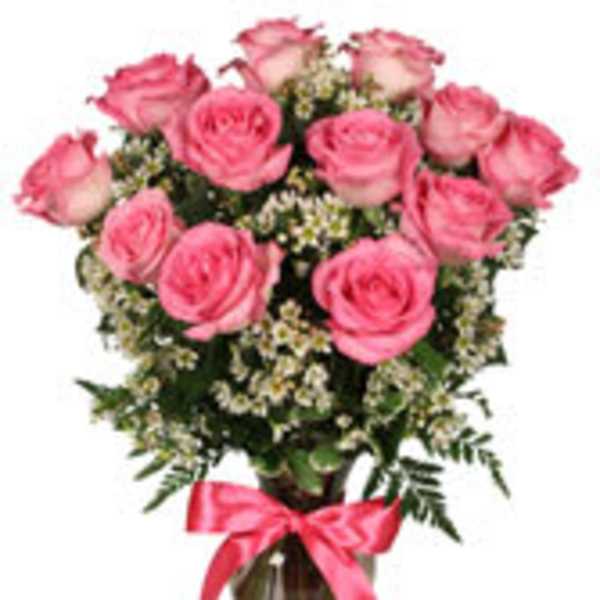 Pink roses arranged in a glass vase with a pink ribbon