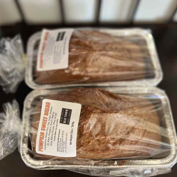 Two wrapped loaves of pumpkin sweet bread in foil pans