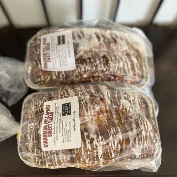 Two packaged loaves of cinnamon pull-apart sweet bread on a table.