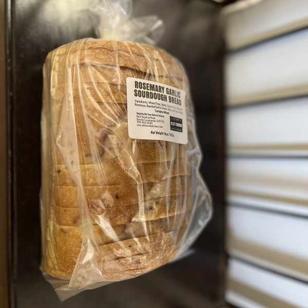 Wrapped loaf of rosemary garlic sourdough bread with a product label