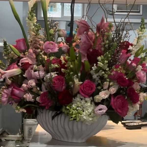 Large pink and white floral arrangement in a white vase