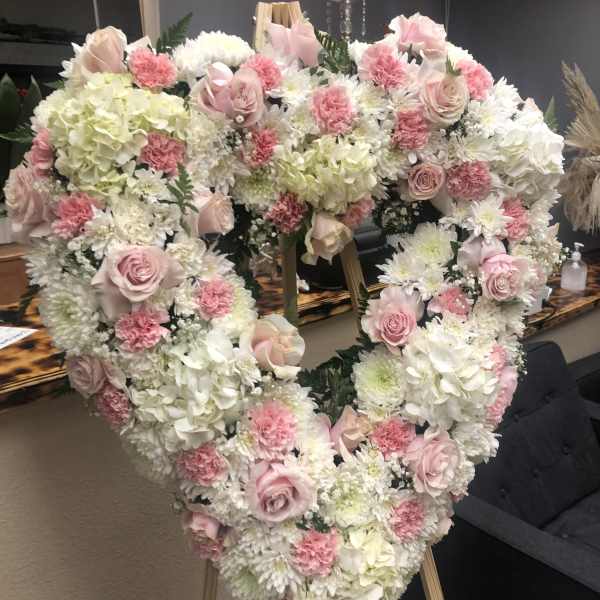 Heart-shaped floral arrangement with pink and white roses and carnations
