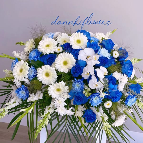 Blue and white floral spray with roses, daisies, and orchids