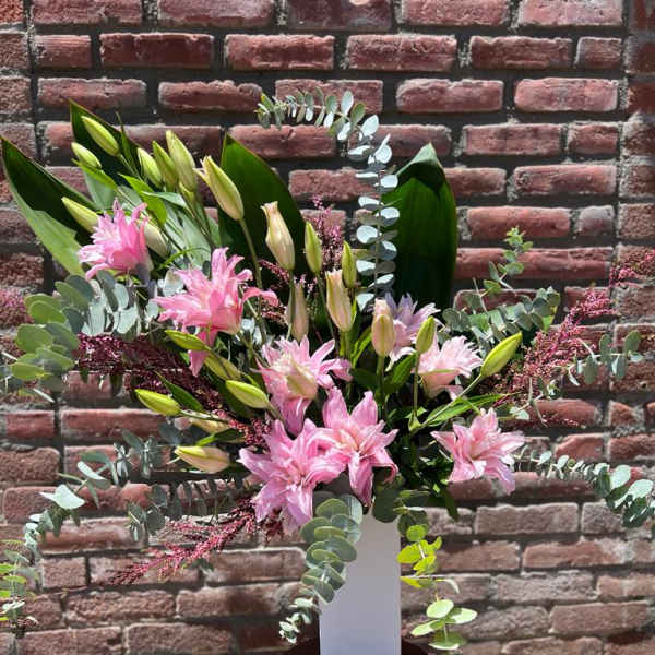 Pink lilies in a white vase with eucalyptus and greenery