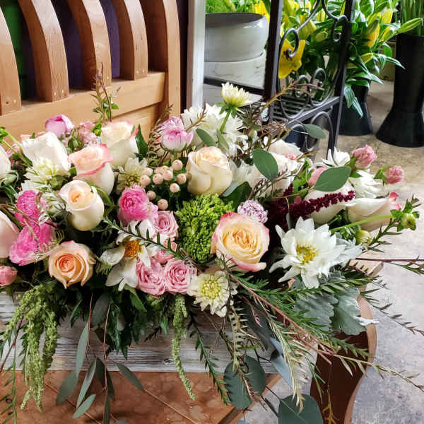 Low centerpiece of pink and cream roses with mixed blooms in a white wooden box