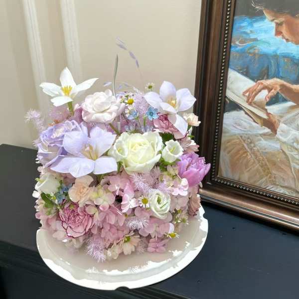 Pastel bouquet with white and lavender flowers in a white tray