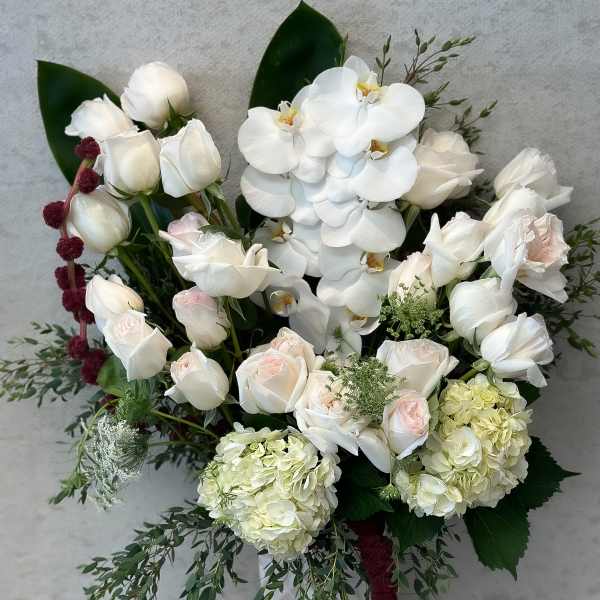 White roses, orchids, and hydrangeas in a white vase