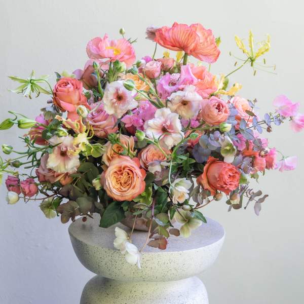Peach and pink floral arrangement in a round stone vase