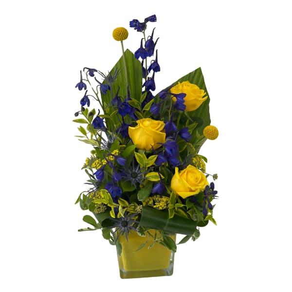 Yellow roses and blue flowers in a square glass vase