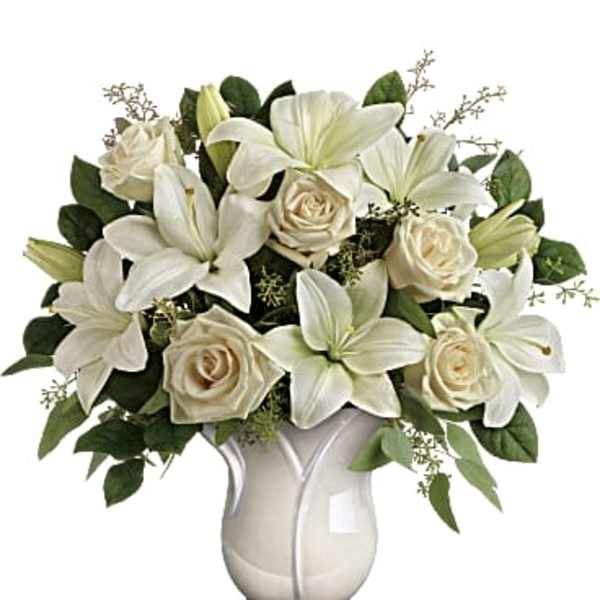 White lilies and cream roses arranged in a white vase