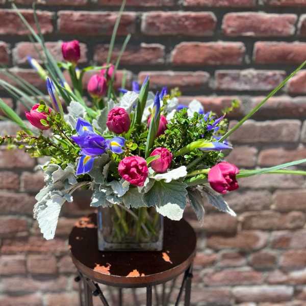 Bouquet of pink and blue flowers in a square glass vase