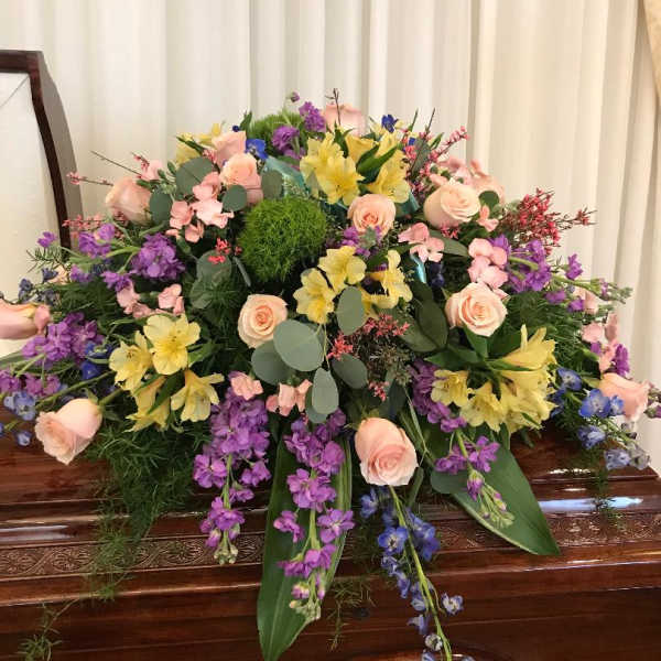 Large pastel floral spray on a wooden casket