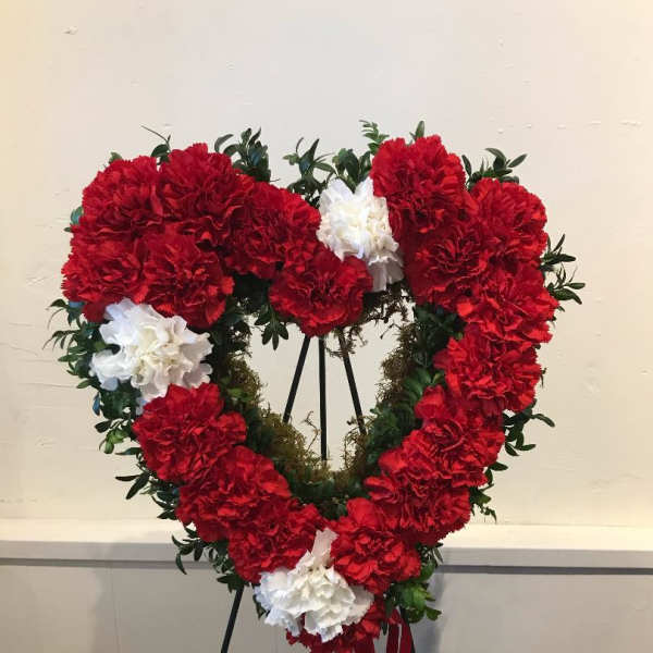 Heart-shaped wreath of red and white carnations on an easel