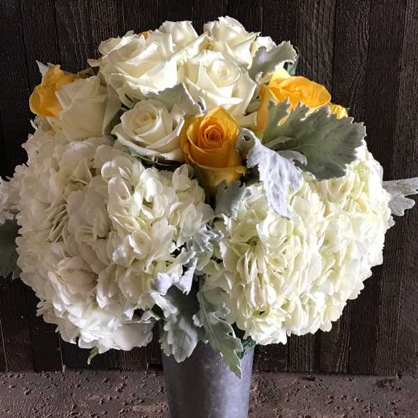 White and yellow rose bouquet in a tall silver vase