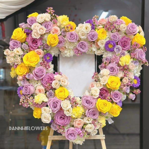 Heart-shaped floral wreath of roses in pink, lavender, white, and yellow