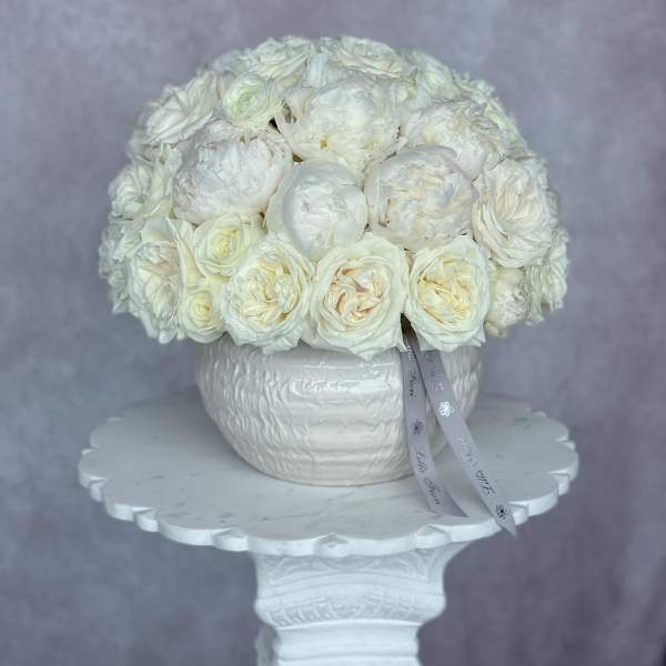 White rose bouquet in a white vase on a pedestal