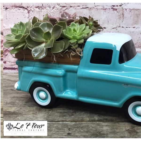 Succulents arranged in a turquoise ceramic pickup truck planter
