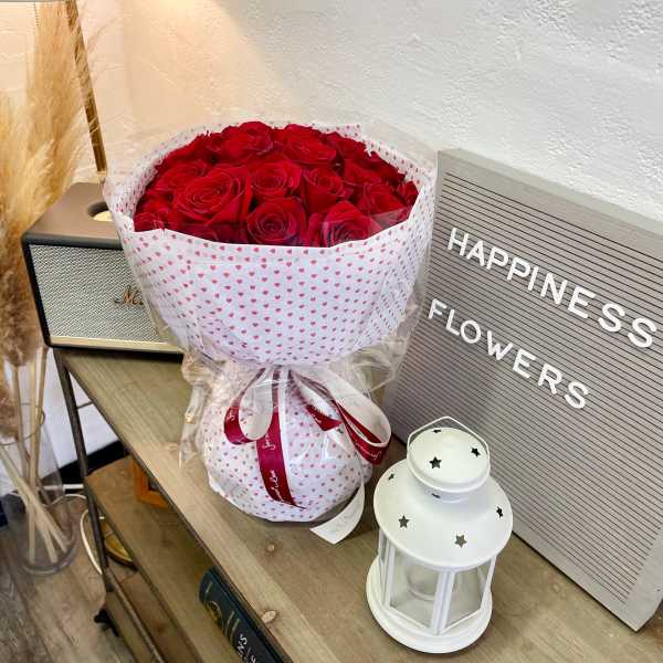 Bouquet of red roses wrapped in white heart-patterned paper