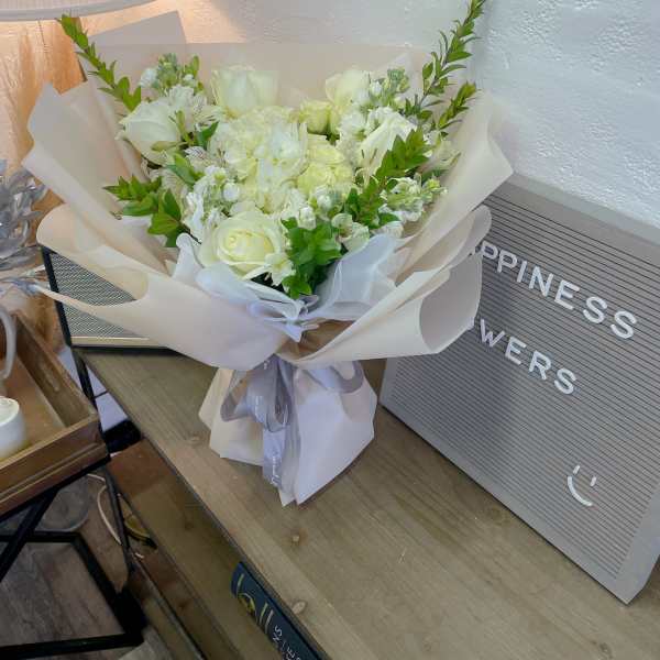 White rose bouquet wrapped in cream paper with a gray ribbon