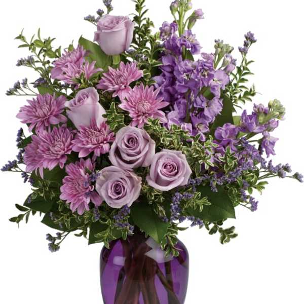 Lavender roses and purple flowers in a purple glass vase