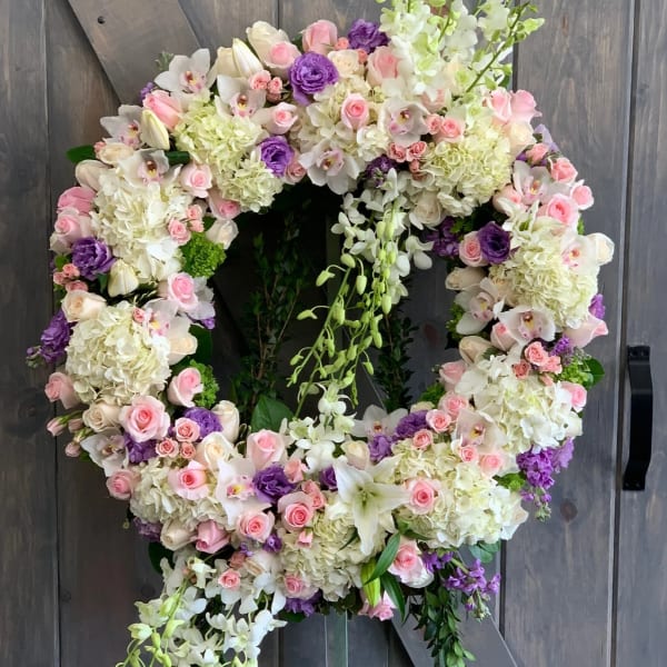 Large floral wreath with pink, white, and purple blooms on a wooden backdrop