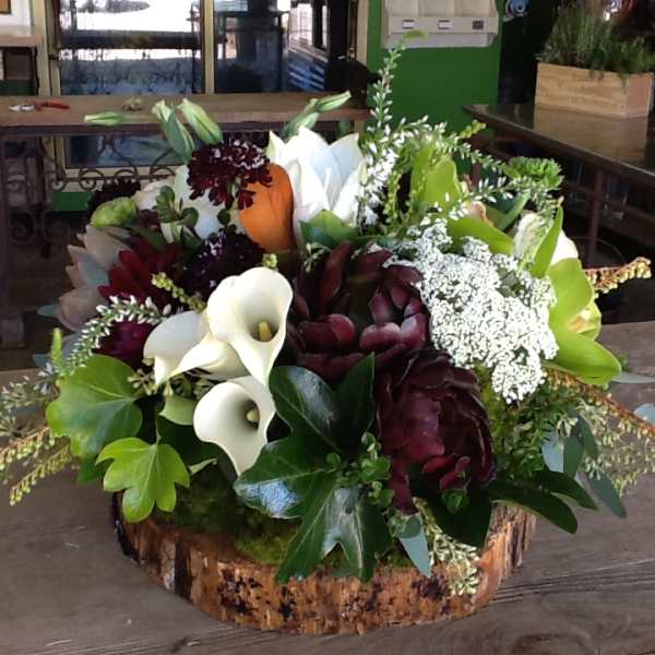 Mixed floral arrangement with white calla lilies and burgundy blooms in a wood base