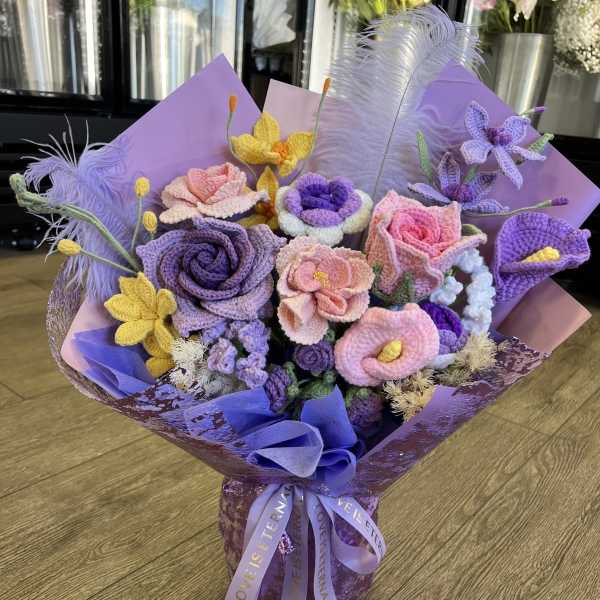 Bouquet of crocheted purple, pink, and yellow flowers wrapped in lavender paper