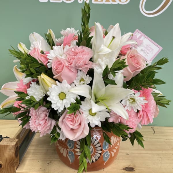 Pink roses and white lilies arranged in a painted ceramic pot
