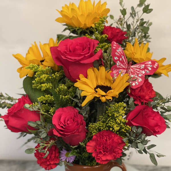 Bouquet of red roses and yellow sunflowers in a painted ceramic vase