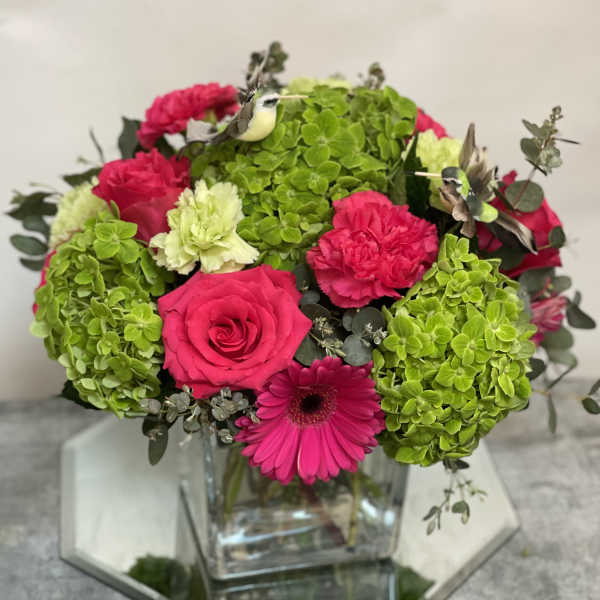 Pink roses and gerbera daisy in a glass vase with green hydrangea