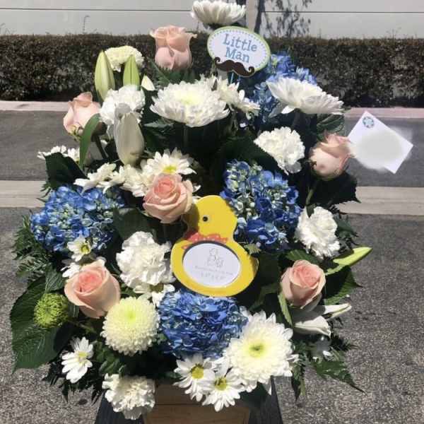 Large floral arrangement with blue hydrangeas, white daisies, and pale pink roses