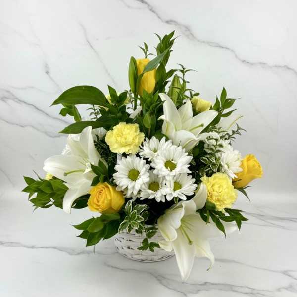 White lilies, yellow roses, and white daisies in a white basket