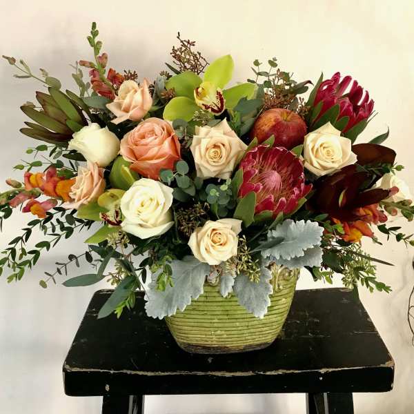 Mixed bouquet of roses and protea in a green vase