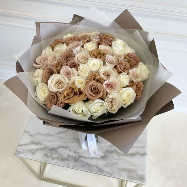 Bouquet of cream and blush roses wrapped in brown and white paper