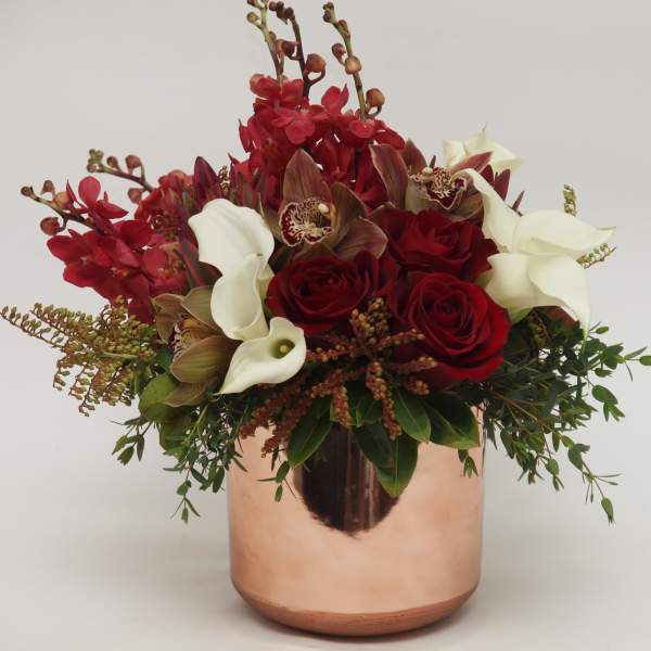 Red roses and white calla lilies in a copper vase